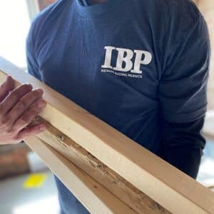 man wearing Installed Building Products tshirt and holding lumber